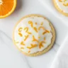 Macro close-up of soft glazed orange juice cookies topped with fresh zest