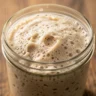 A close-up of a bubbly, active sourdough starter in a glass jar, ready for baking.