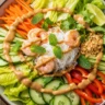 Deconstructed spring roll salad with shrimp, noodles, fresh vegetables, and creamy peanut dressing in a rustic bowl.