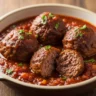 Macro close-up of tender braised beef meatballs in rich umami tomato sauce, garnished with fresh parsley.