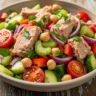 Close-up of vibrant Mediterranean Tuna & Garbanzo Power Salad in a rustic bowl, bursting with fresh vegetables and lemon-herb dressing.