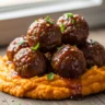 Melt-in-Your-Mouth Maple Glazed Beef Meatballs with Fluffy Sweet Potato Mash, garnished with fresh parsley and red pepper flakes on a rustic wooden surface.