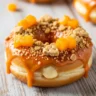 Macro close-up of a baked peach cobbler cheesecake donut with spiced peach glaze, graham crackers, and fresh peaches on a rustic wooden board.