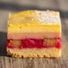 Macro close-up of a Golden Sunset Rhubarb Custard Dream Bar slice with distinct layers and powdered sugar.