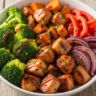 Zesty Maple Dijon Chicken Sweet Potato Power Bowl with roasted vegetables and glazed chicken, garnished with fresh thyme.