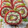 Macro close-up of Zesty Keto Beef Salami Pinwheels garnished with fresh dill on a rustic wooden board.