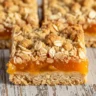 Macro close-up of a Golden Apricot-Orange Salt River Bar with a golden crumble topping and vibrant fruit filling.