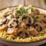 Close-up of creamy chicken stroganoff with mushrooms, parsley, and egg noodles.