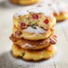 Macro close-up of crispy golden rhubarb fritters dusted with powdered sugar on a rustic wooden board, showing a soft interior with diced rhubarb.