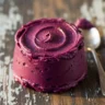 Macro close-up of rich, velvety slow cooker blueberry butter with a glossy sheen on a rustic wooden surface, highlighting its smooth texture and deep purple color.