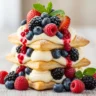 Macro close-up of a Velvet Berry Dream Pastry Stack with golden puff pastry, vanilla cream, and fresh mixed berries dusted with sugar.
