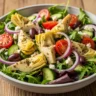 Close-up of a vibrant Tuscan Artichoke and Tomato Salad Bowl with vegan feta, olives, and a herbaceous dressing, served in a rustic ceramic bowl on a wooden table.