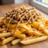 Close-up of golden crispy Air Fryer Animal Style Fries loaded with gooey melted American cheese, deeply caramelized onions, and tangy secret sauce.