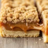 Macro close-up of a sliced caramel crush bar showing gooey caramel, shortbread, and crumble layers.