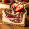 Macro close-up of a slice of Velvety Chicago Chocolate Strawberry Swirl Cheesecake Dream with chocolate and strawberry swirls on a rustic wood surface.