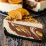 Macro close-up of a slice of Velvety Chocolate Orange Dream Cheesecake with marbled chocolate swirls, orange zest, and a thick chocolate cookie crust on a rustic wooden table.