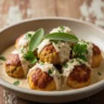 Macro close-up of Cozy Autumn Pumpkin Chicken Meatballs in creamy sage sauce, garnished with fresh herbs, on a rustic wooden surface.