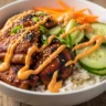 Macro close-up of a vibrant Korean BBQ Chicken Bowl with caramelized chicken, fresh vegetables, and zesty gochujang cream sauce.