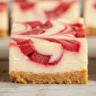 Sweet-Tart Rhubarb Swirl Cheesecake Bar with vibrant pink rhubarb swirls on a creamy white filling and golden shortbread crust.