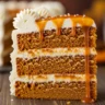 A decadent slice of Spiced Pumpkin Dream Cake with Salted Caramel and Cream Cheese Frosting, beautifully plated on a rustic wooden surface.